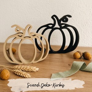 Könnte beinhalten: Zwei kürbisförmige Dekorationsobjekte, eines in Beige und eines in Schwarz, mit einem hohlen, linearen Design und einem Stiel. Der Text "Scandi Deko-Kürbis" steht unten und das Logo "Wunschkram & Herzgemachtes" befindet sich in der oberen rechten Ecke.