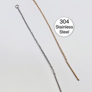 May include: Two stainless steel chain earrings, one silver and one gold, with a straight bar at the end. The earrings are shown against a white background. The text "304 Stainless Steel" is in a white circle.