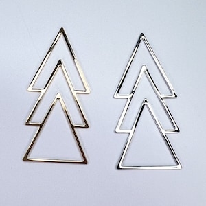 May include: A pair of gold and silver triangle earrings. Each earring is made of three triangles, one inside the other, forming a tree shape.
