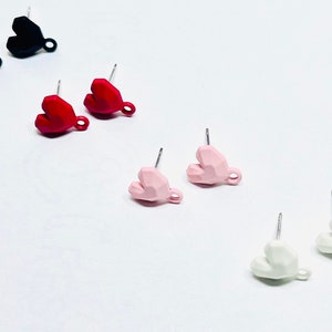 May include: A set of six geometric heart-shaped earrings in black, red, pink, and white. Each earring has a small loop at the bottom.