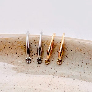 May include: Three jump rings in different finishes: silver, gold, and rose gold. The jump rings are all the same size and shape, with a slightly curved design.