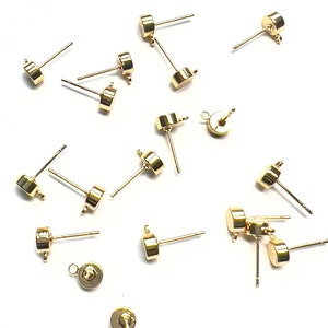 K&ouml;nnte beinhalten: Eine Gruppe von 14 goldfarbenen Ohrring-Findings mit rundem Kopf und gerader Stift. Die Findings haben eine &Ouml;se oben zum Anbringen eines Charms oder einer Perle.