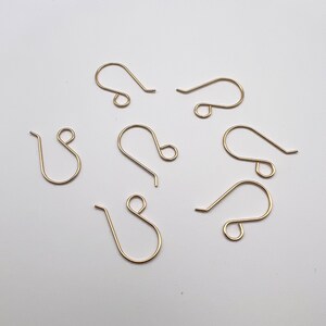 May include: A set of six gold-toned earring hooks. The hooks are made of metal and have a simple, classic design.