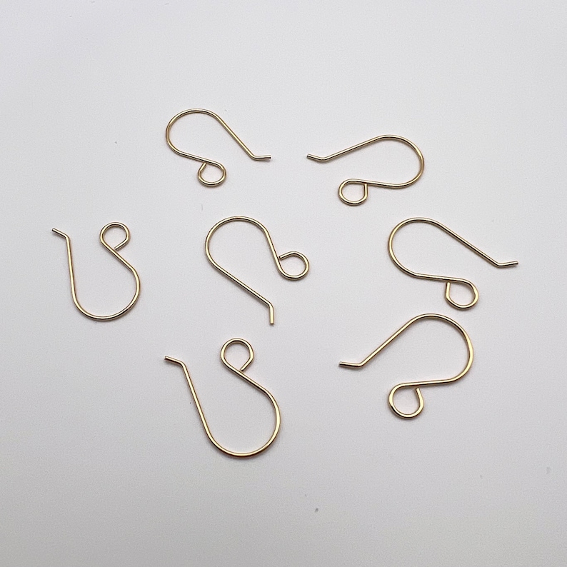 May include: A set of six gold-toned earring hooks. The hooks are made of metal and have a simple, classic design.