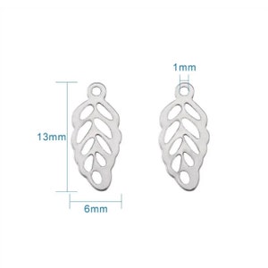 May include: Two silver leaf-shaped charms with a cutout design. Each charm measures 13 mm in length, 6 mm in width, and 1 mm in thickness.