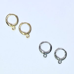 May include: Four earring hoops, two gold and two silver, with a hinged closure. The hoops are simple and elegant.