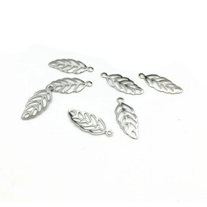 May include: Six silver leaf-shaped charms with a cut-out design. Each charm has a small loop at the top for attaching to jewelry or other crafts.