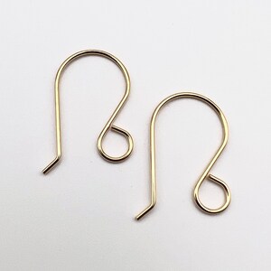 May include: A pair of gold-toned earring hooks. The hooks are made of metal and have a simple, elegant design.