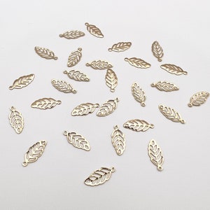May include: A collection of gold-colored metal leaf charms. The charms are delicate and intricate, with a cutout design. They are perfect for adding a touch of elegance to jewelry or crafts.