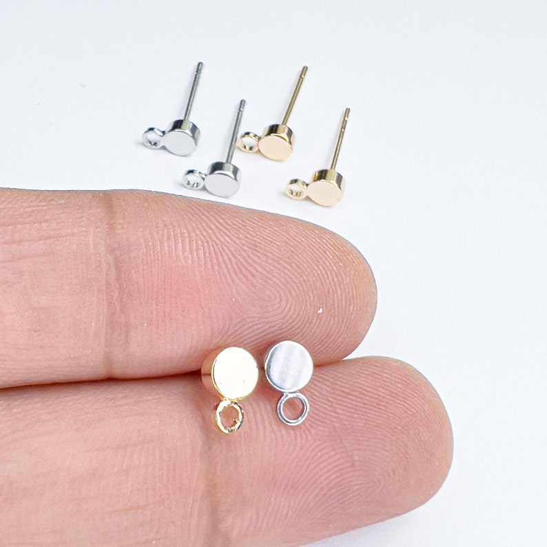 K&ouml;nnte beinhalten: Drei Paar Ohrring-Verschl&uuml;sse mit rundem Kopf und einer kleinen Schlaufe. Die Verschl&uuml;sse sind silber, gold und eine Mischung aus silber und gold.
