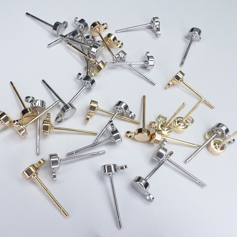 K&ouml;nnte beinhalten: Eine Sammlung von silbernen und goldenen Ohrring-Stiften mit verschiedenen Arten von Ohrring-R&uuml;cken. Die Ohrring-Stifte sind alle etwa 2,5 cm lang.