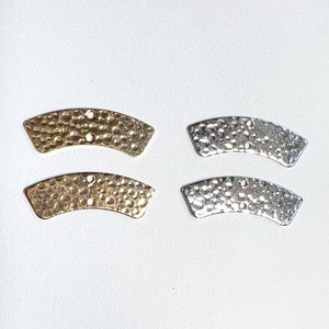 May include: Four hammered metal arc-shaped jewelry components. Two are gold-toned, and two are silver-toned. Each piece has two small holes for attaching to other components. The pieces have a textured, dimpled surface.