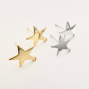 May include: Two pairs of star-shaped stud earrings. One pair is gold-colored, and the other is silver-colored. Each earring has a post for piercing and a small loop at the bottom of the star.