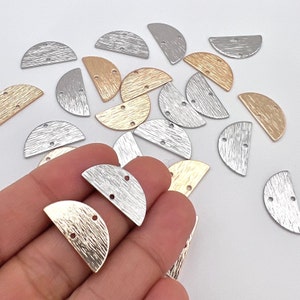 Op de afbeelding: Een verzameling halfronde metalen sieradenonderdelen in goud, zilver en brons. Elk stuk heeft een getextureerd oppervlak en twee kleine gaatjes voor bevestiging. De onderdelen liggen op een witte ondergrond.