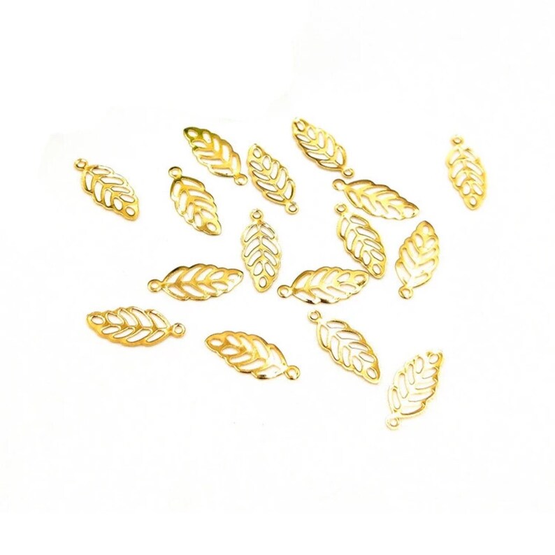 May include: A scattering of 16 gold leaf charms, each with a delicate, intricate design. The charms are perfect for adding a touch of elegance to jewelry making projects.