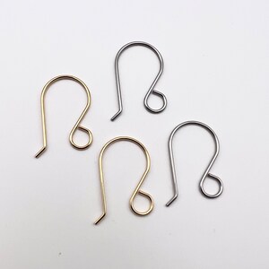 May include: Four earring hooks in different finishes: gold, silver, and two shades of silver. The hooks are all the same size and shape.
