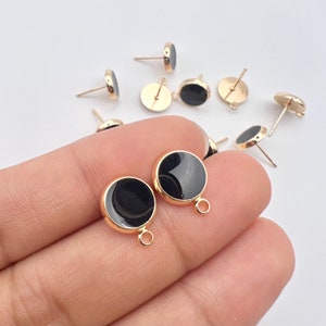 May include: A close-up of ten gold-toned earring posts with black round cabochons. The earring posts have a small loop at the end.