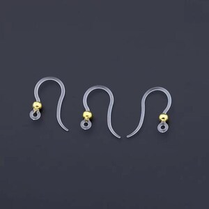 May include: Clear plastic earring hooks with gold-colored ball accents. The hooks are curved and designed for pierced ears. The gold accents add a touch of elegance to the simple design. These are ideal for DIY jewelry making.