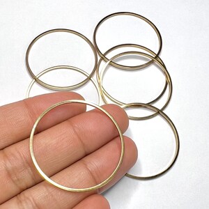 May include: A set of five gold-coloured metal hoops of varying sizes. The hoops are arranged in a stack, with the largest hoop at the bottom and the smallest hoop at the top.