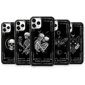 Peut inclure: Ensemble de six coques d'iPhone noires avec des motifs blancs représentant des images de cartes de tarot. Les motifs incluent la Mort, l'As d'Épées, les Amoureux, l'Éclipse et le Sphinx.
