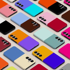 May include: A collection of smartphone cases arranged in a grid pattern, each featuring a two-tone color block design. The cases display various vibrant color combinations, including orange, pink, blue, black, white, yellow, and purple.