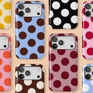 May include: A collection of smartphone cases with various polka dot patterns. Designs include brown dots on a light blue background, white dots on black, and red dots on pink. The cases have a glossy finish.