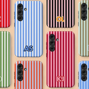 May include: A collection of smartphone cases with vertical stripe patterns in various colors, including blue, red, green, and brown. Some cases feature initials such as "AS", "OL", and "KJ". The cases have a camera module.