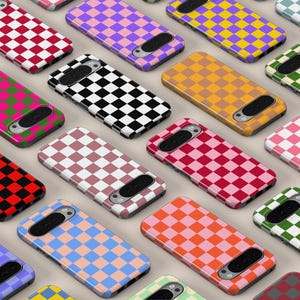 Puede incluir: Una colección de fundas para smartphone dispuestas en un patrón de cuadrícula, cada una con un diseño de tablero de ajedrez bicolores distinto. Las fundas muestran varias combinaciones de colores, incluyendo rojo, negro, morado, amarillo, naranja, verde, rosa y azul.