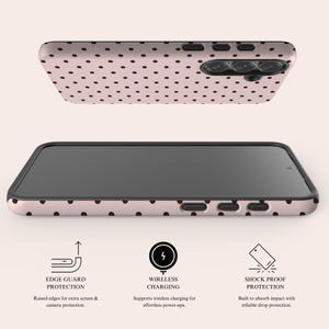 May include: A phone case with a pink background and a pattern of small brown polka dots. The case has raised edges for screen and camera protection, supports wireless charging, and is shock-proof. The image shows the phone case from two different angles.