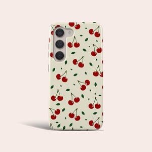 May include: A white phone case with a pattern of red cherries and green leaves.