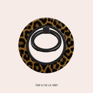 May include: A round phone grip with a leopard print design and a black ring. The grip has a black ring that swivels. The text "THE LUXE GUARD" is at the bottom.