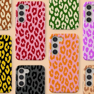 Puede incluir: Una colección de fundas para teléfonos con diseño de estampado de leopardo en varios colores. Las fundas tienen un acabado brillante y un recorte para la cámara. Los colores incluyen rosa, rojo, naranja, verde, morado, negro y marrón. Fondo beige claro.