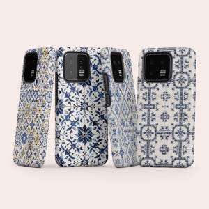 May include: Four rectangular smartphone cases featuring various blue and white tile-inspired patterns. Each case has a black camera module cutout with the text LEICA printed on it. The designs include intricate floral, geometric, and star motifs.