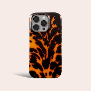 Op de afbeelding: Een smartphonehoesje met een schildpadpatroon in zwart en oranje. De hoes heeft een glanzende afwerking en een cameramodule met meerdere lenzen.