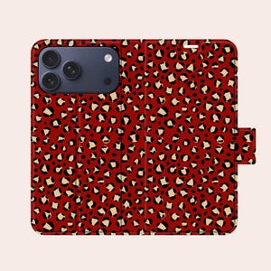 May include: A red phone case with a leopard print pattern. The case has black and beige spots across its surface. The phone case is closed and has a magnetic clasp.