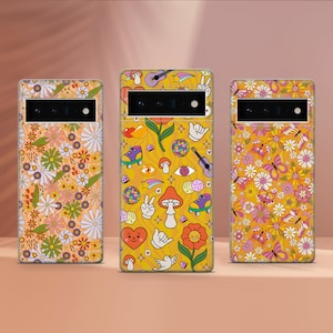 May include: Three phone cases with different designs. The first case has a floral pattern with yellow, orange, and white flowers. The second case has a yellow background with a variety of colourful retro designs, including a mushroom, a peace sign, and a disco ball. The third case has a yellow background with a floral pattern with pink, yellow, and white flowers.