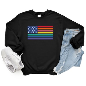 May include: Black sweatshirt with a rainbow pride flag design superimposed on a traditional American flag. The flag has red, orange, yellow, green, blue, and purple stripes.