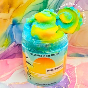 以下が含まれることがあります： 渦巻き模様の青と黄色のバススクラブが入ったガラス瓶。瓶には「Philosophy in the Making」と「Embrace Tranquility」と書かれたラベルが貼られています。