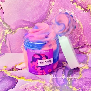 Puede incluir: Un slime de color rosa y azul en espiral en un frasco transparente con tapa blanca. El frasco tiene una etiqueta que dice "Philosophy in the Making" y "Girl Power Slime". El slime está etiquetado como "Bubblegum Fragrance".