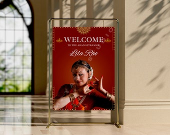 Pode incluir: Um sinal de boas-vindas vermelho com detalhes dourados e uma imagem de uma mulher com roupas tradicionais indianas. O sinal diz "Bem-vindo ao arangetram de Lila Rao".