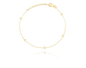 May include: A delicate gold chain bracelet with small round beads. The bracelet has a lobster clasp closure.