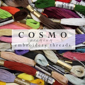 May include: A selection of Cosmo premium embroidery threads in a variety of colours, such as green, orange, pink, and purple. The image shows numerous spools of thread with labels and the text "COSMO premium embroidery threads".