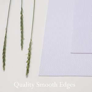 K&ouml;nnte beinhalten: Wei&szlig;er Canvas-Stoff mit einer glatten, gleichm&auml;&szlig;igen Textur und wei&szlig;em Hintergrund. Der Text "Quality Smooth Edges" ist unter dem Stoff gedruckt.