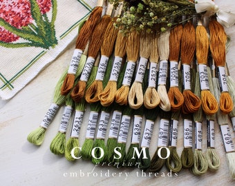 May include: A collection of 20 skeins of embroidery floss in shades of green, yellow, and brown. The floss is labeled with the brand name "COSMO" and the numbers 578, 577A, 576, 575A, 574, 573, 2573, 705A, 706, 703, 704, 630A, 2631, 6332, 633, 635A, 636, 637, 687, 685, 686, 684, 683, 682, 681.