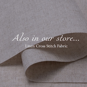 K&ouml;nnte beinhalten: Nahaufnahme eines beigefarbenen Leinenstoffs mit gewebter Struktur. Der Stoff ist &uuml;ber sich selbst gefaltet und der Text "Also in our store... Linen Cross Stitch Fabric" ist sichtbar.