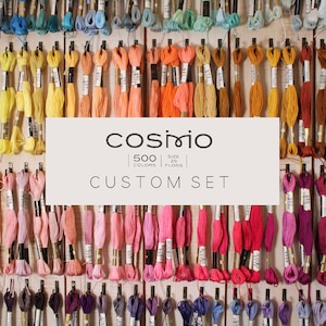 May include: A wall display of 500 colors of embroidery floss in a variety of shades, organized by color family. The floss is labeled "COSMIO 500 Colors Silk 25  Floss CUSTOM SET".