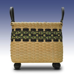 May include: A woven basket with black leather handles and a green and black geometric design. The basket has a rectangular shape and sits on four black wooden feet.