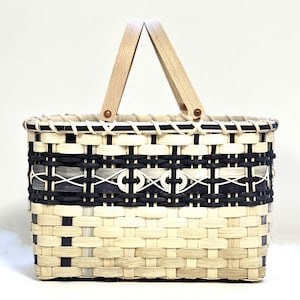 May include: A rectangular woven basket with a black and white pattern. The basket has a wooden handle and is made of natural materials.