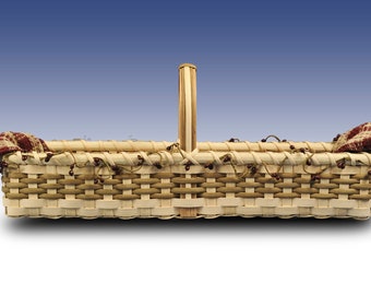 May include: A rectangular woven basket with a handle and fabric lining. The basket is made of natural wood and has a light brown color. The fabric lining is red and white with a plaid pattern.
