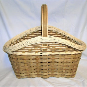 May include: A woven basket with a light brown and white pattern. The basket has a handle and a rounded, oval shape.
